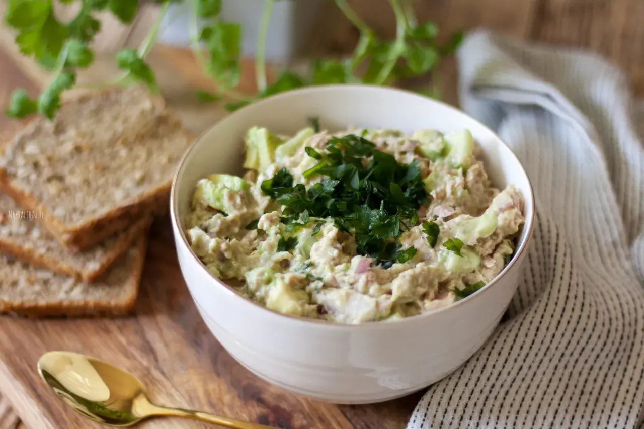 Pyszna pasta z awokado i tuńczyka, udekorowana natką pietruszki, podana z chlebem.
