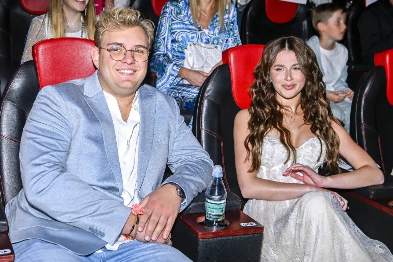 Roksana Węgiel i jej mąż, Kevin Mglej, siedzą w kinie. Ona w białej sukni, on w błękitnej marynarce.