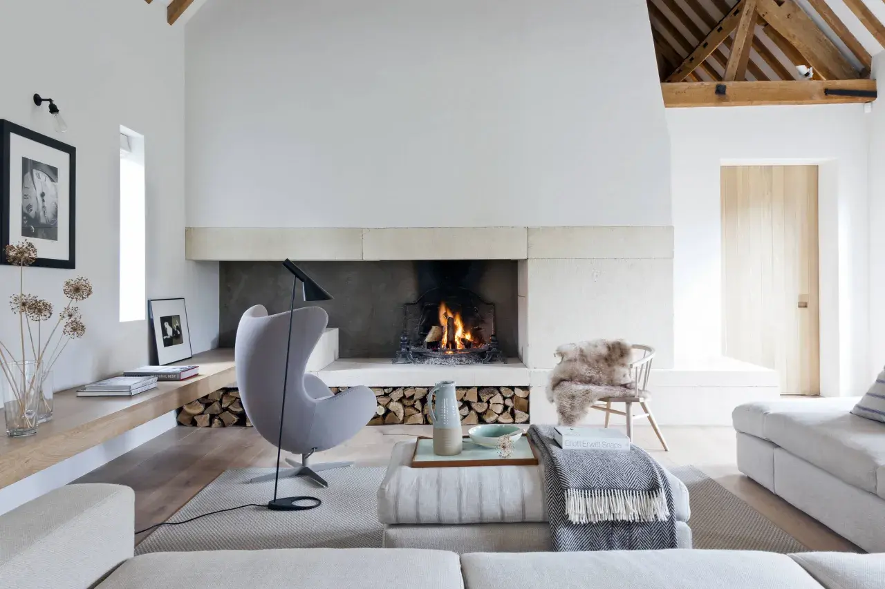 Acogedor salón con un mueble con chimenea encendida, sillón gris, sofás y decoración rústica.
