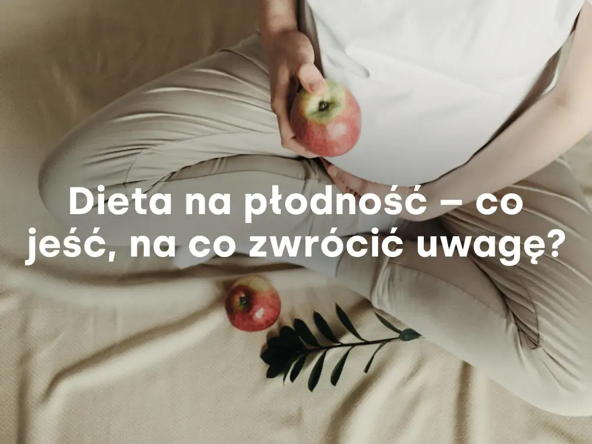 Kobieta w ciąży trzyma jabłko, obok leży drugie jabłko i gałązka.