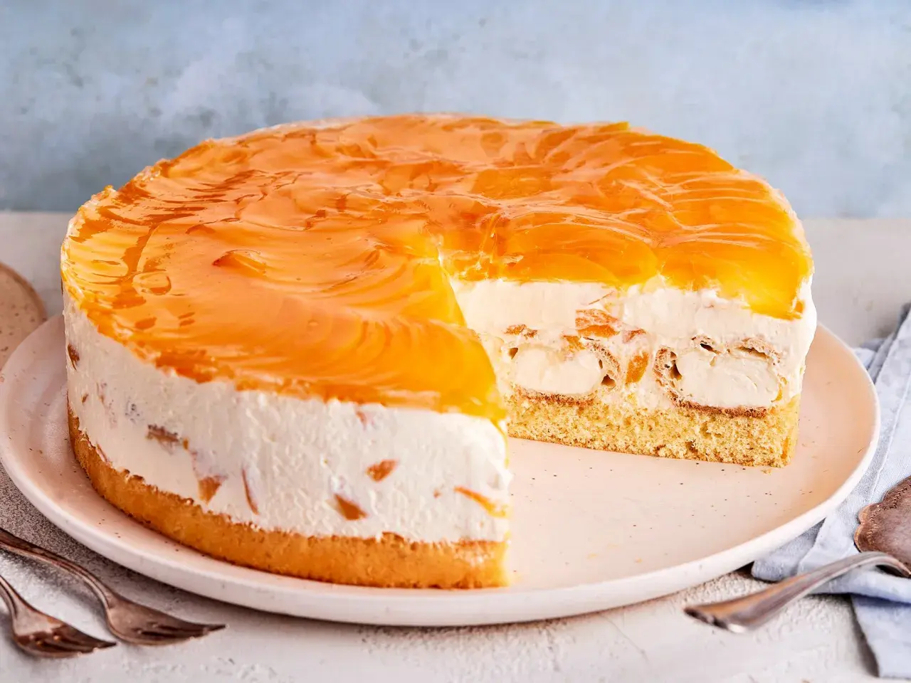 Ein köstliches Windbeuteltorte Rezept: saftiger Boden, cremige Füllung mit Windbeuteln und Pfirsichspalten, überzogen mit glänzendem Pfirsichgelee.
