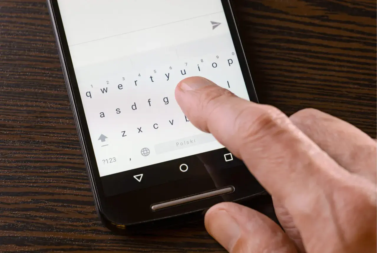 Palec naciska klawisz "u" na klawiaturze telefonu Xiaomi. Dowiedz się, jak wyłączyć wibracje przy pisaniu.
