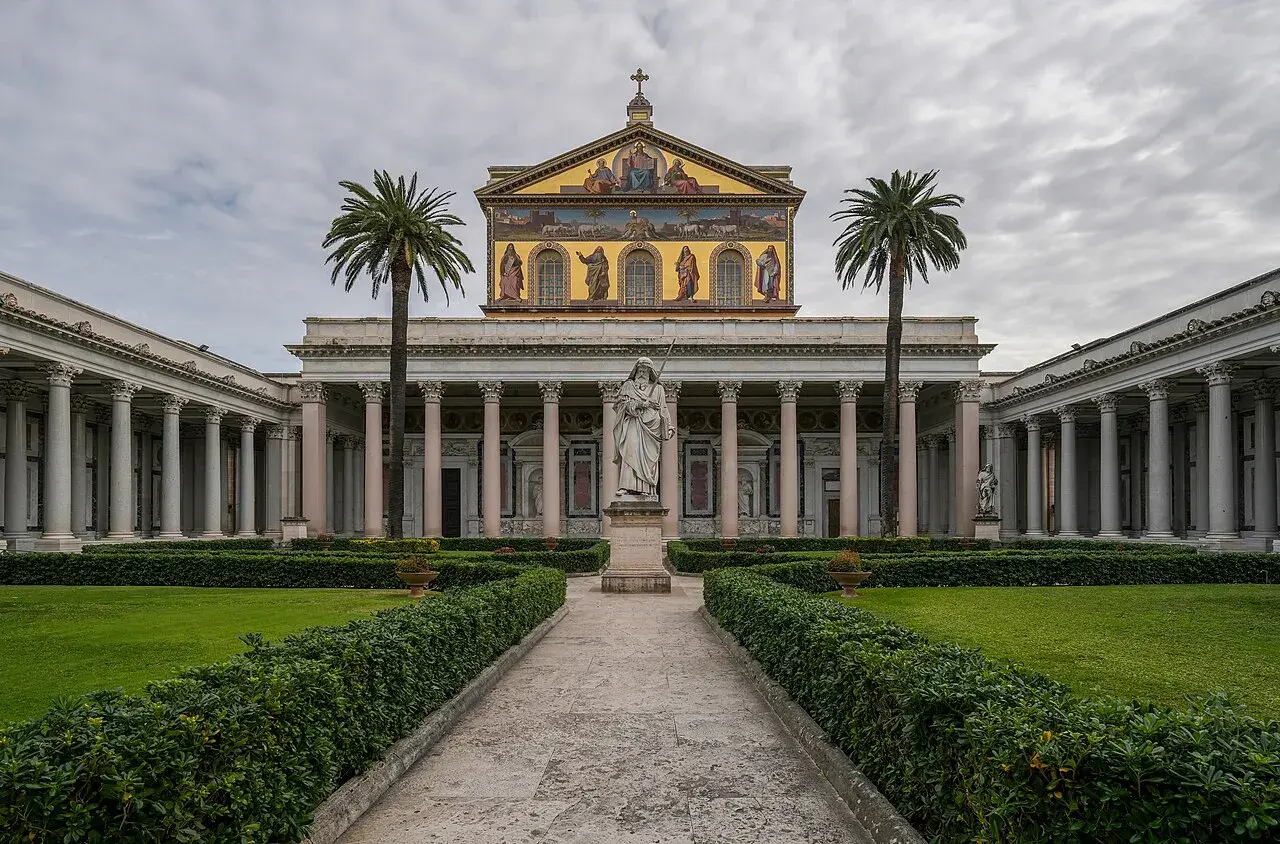Il cortile della cattedrale San Paolo a Roma, con statue e palme, invita alla contemplazione.