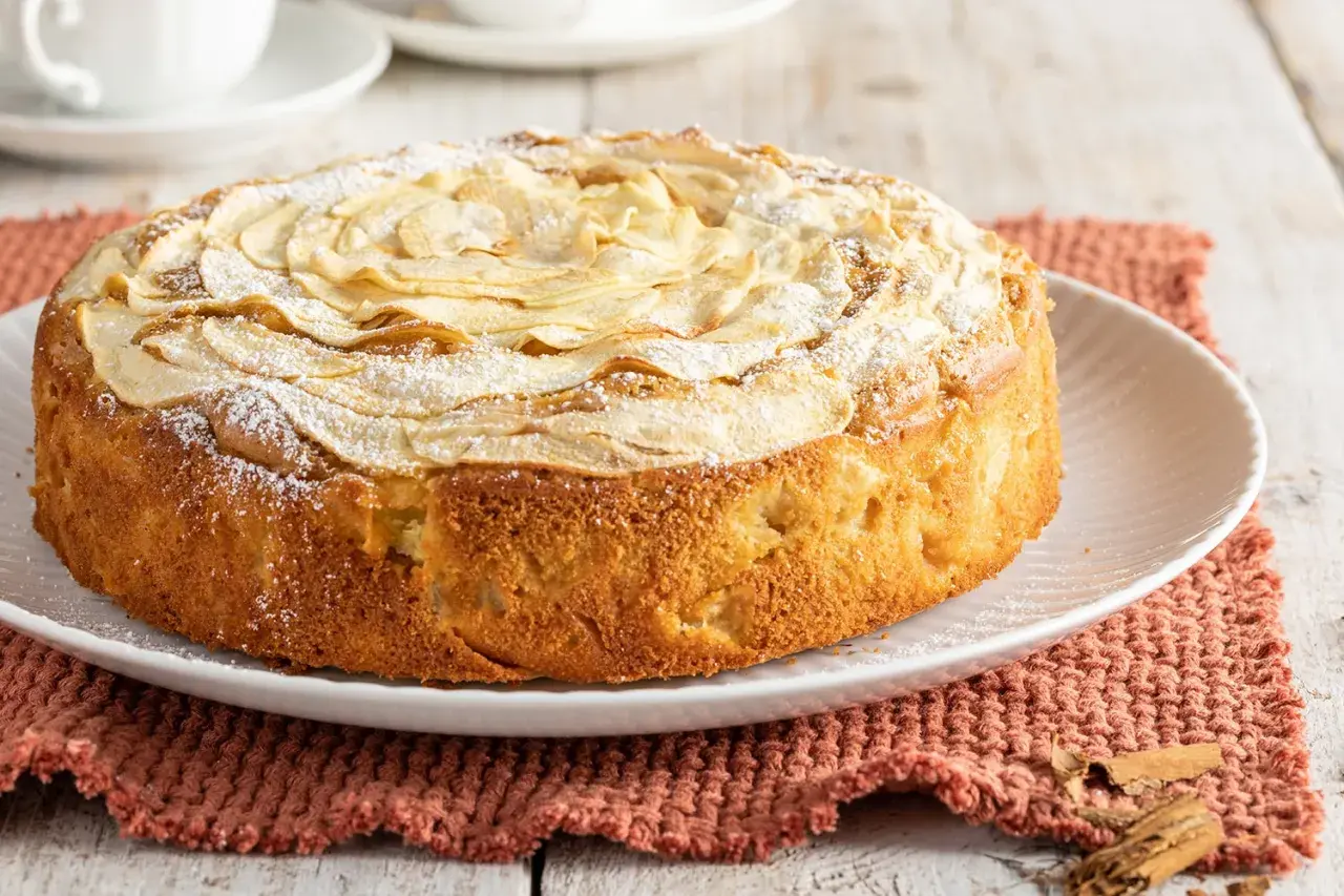 Una deliziosa torta di mele senza burro, decorata con fettine di mela e zucchero a velo, pronta per essere gustata.