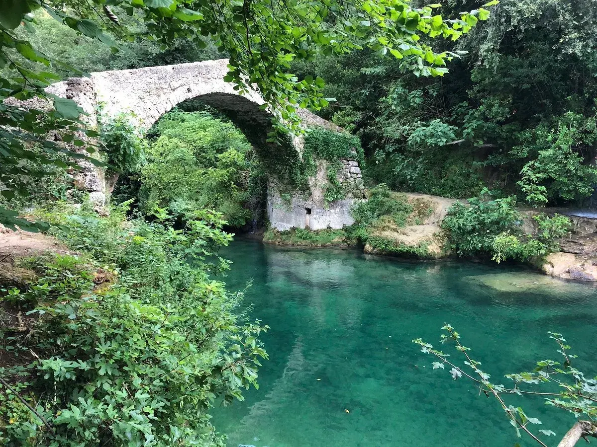 Un pont de pierre enjambe les eaux turquoise des gorges de la Siagne, entouré d'une végétation luxuriante.