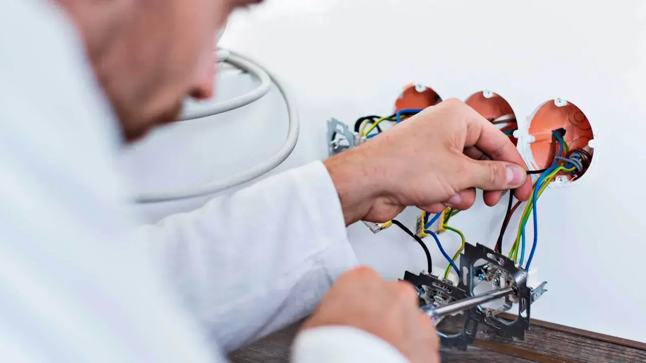 Elektryk podczas wymiany instalacji elektrycznej w mieszkaniu podłącza przewody do puszek.