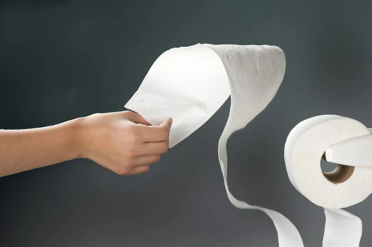 Mano desenrollando papel higiénico. Si sufres gastroenteritis, cómo curar es una pregunta común.