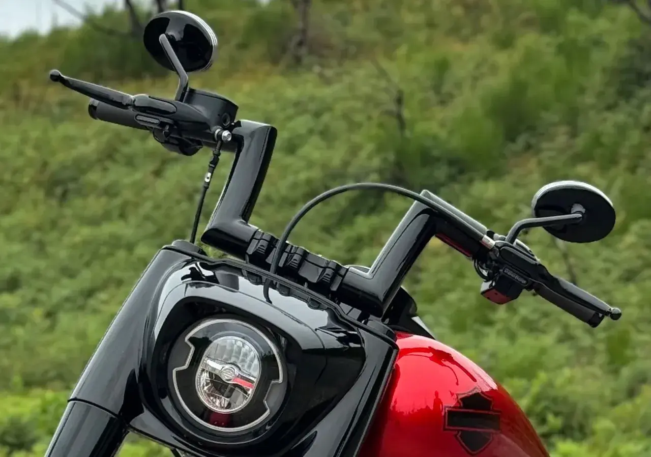Manubrio drag bar Harley nero lucido, con specchietti e faro tondo.