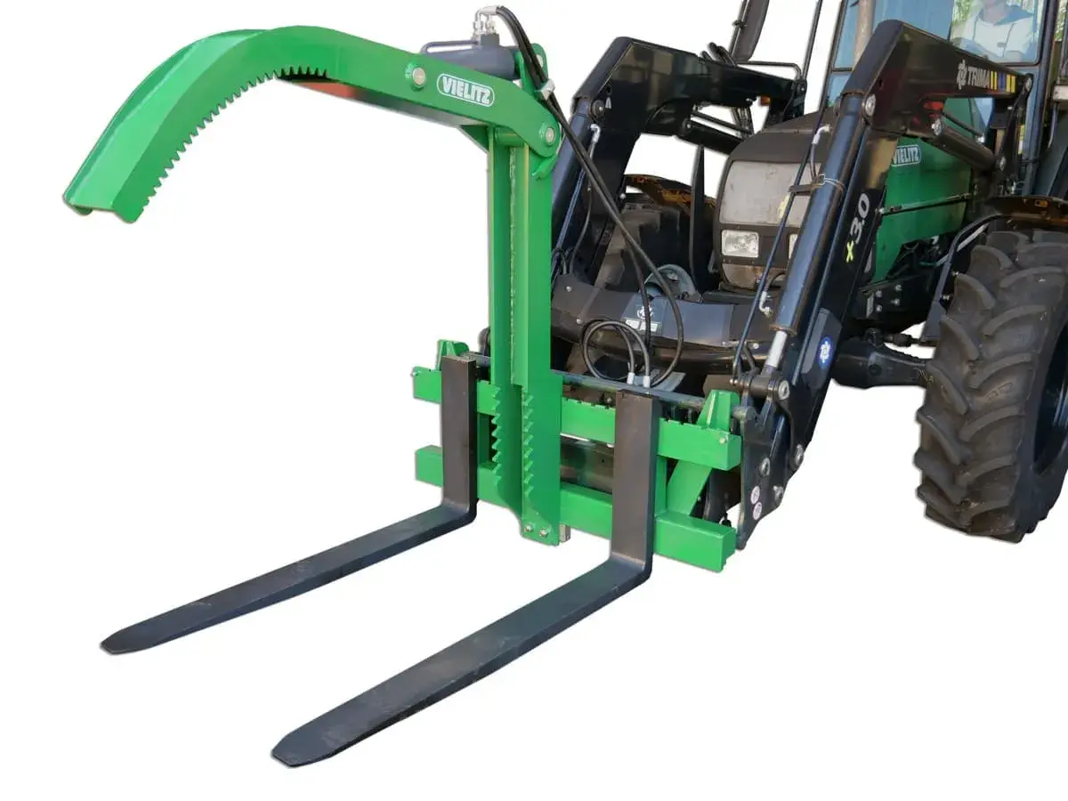 Grüner Greifer für Palettengabel, montiert an einem Traktor. Ideal zum sicheren Transport von Rundholz oder anderen sperrigen Lasten.