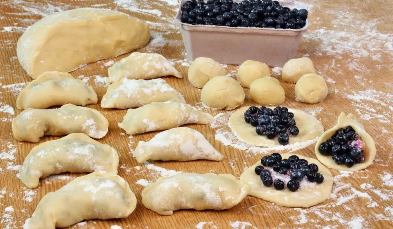 Przygotowania do tego, jak zrobić pierogi z jagodami: ciasto, kulki ciasta, gotowe pierogi i te w trakcie lepienia z jagodami.