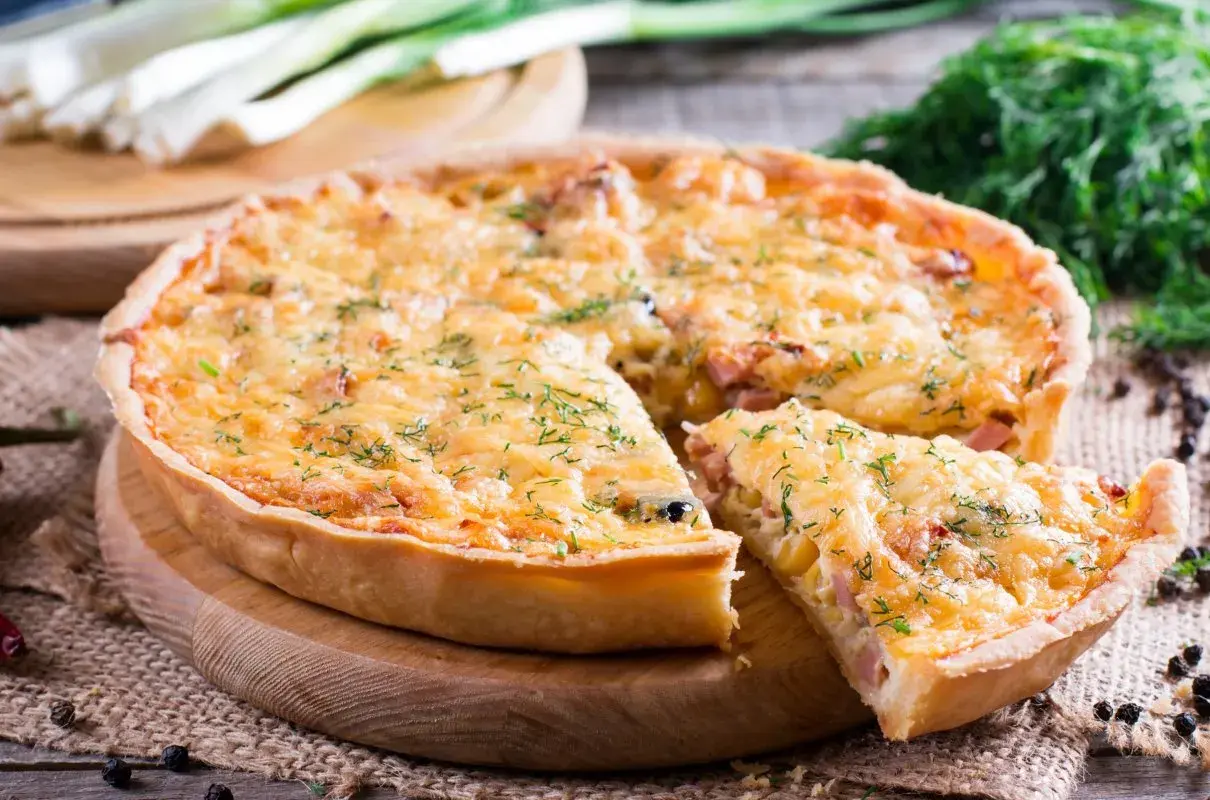 Pyszny quiche z serem i szynką, idealny do wypróbowania z naszymi przepisami. Posypany świeżym koperkiem.
