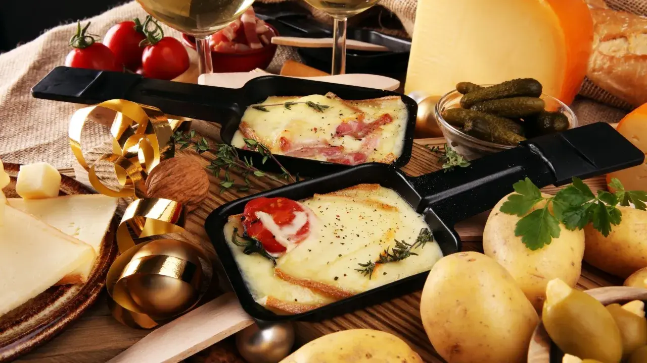 Comment présenter une raclette : fromage fondu, pommes de terre, cornichons et charcuterie, le tout prêt à être dégusté.