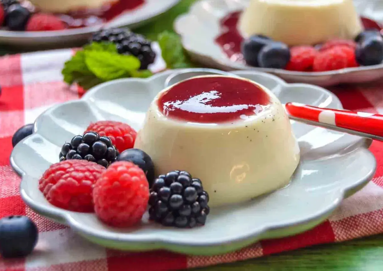 Cremige Panna Cotta mit Beeren und roter Soße, ein Genuss für Augen und Gaumen.