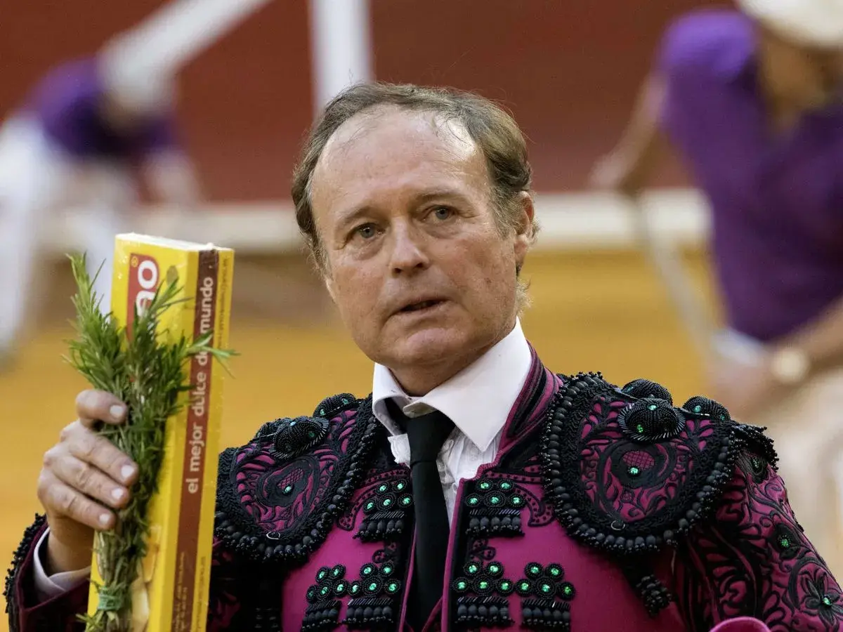 José Vázquez, torero con traje de luces, sostiene un ramo de romero y una caja amarilla.
