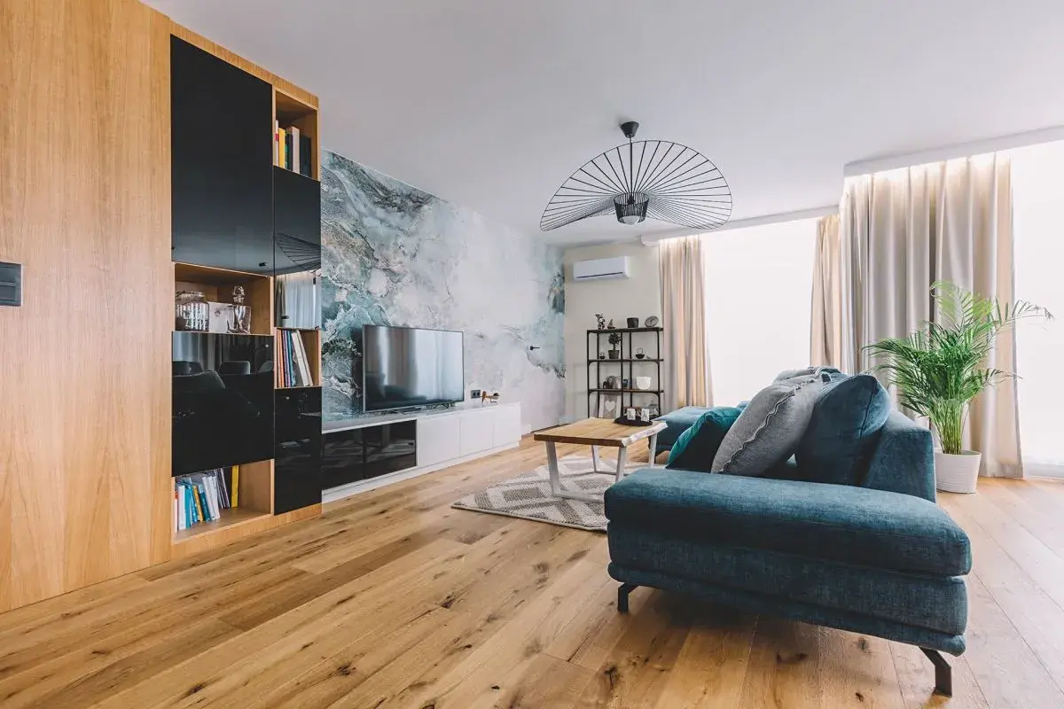Nowoczesny salon z sofą w odcieniach turkusu i szarości, gdzie dominują zimne kolory. Marmurowa ściana dodaje elegancji.
