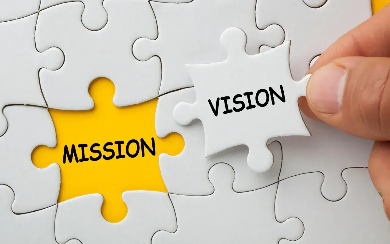 Dłoń dopasowuje element układanki z napisem "VISION" do pola z napisem "MISSION", symbolizując wizję firmy.