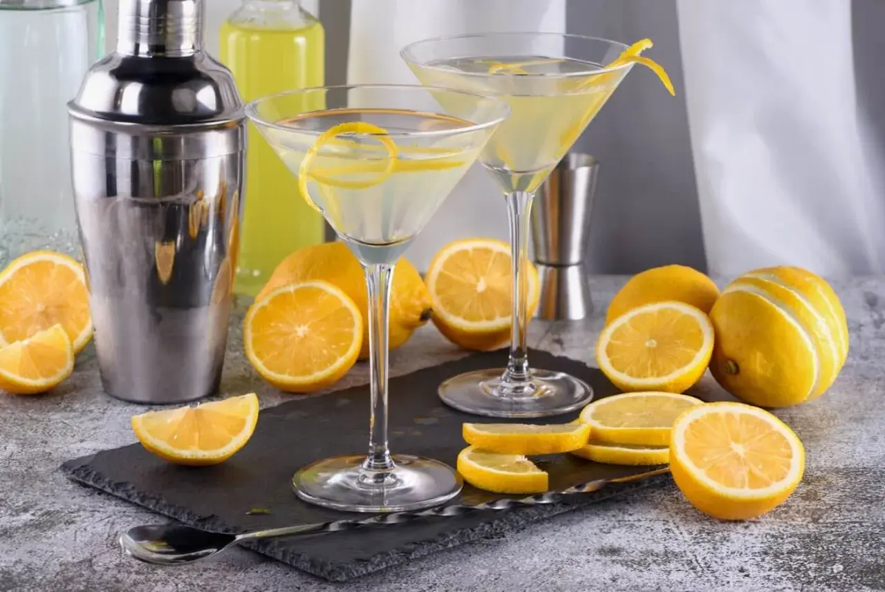 Dwa kieliszki z martini, cytryny i shaker. Idealne na orzeźwiający drink.
