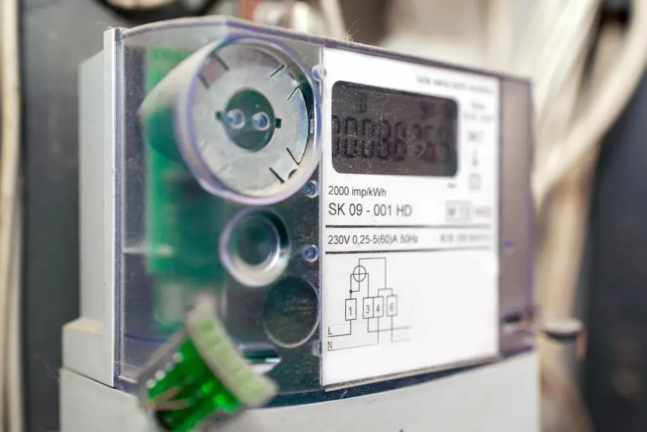 Cyfrowy licznik energii elektrycznej z widocznym wyświetlaczem i schematem podłączenia.