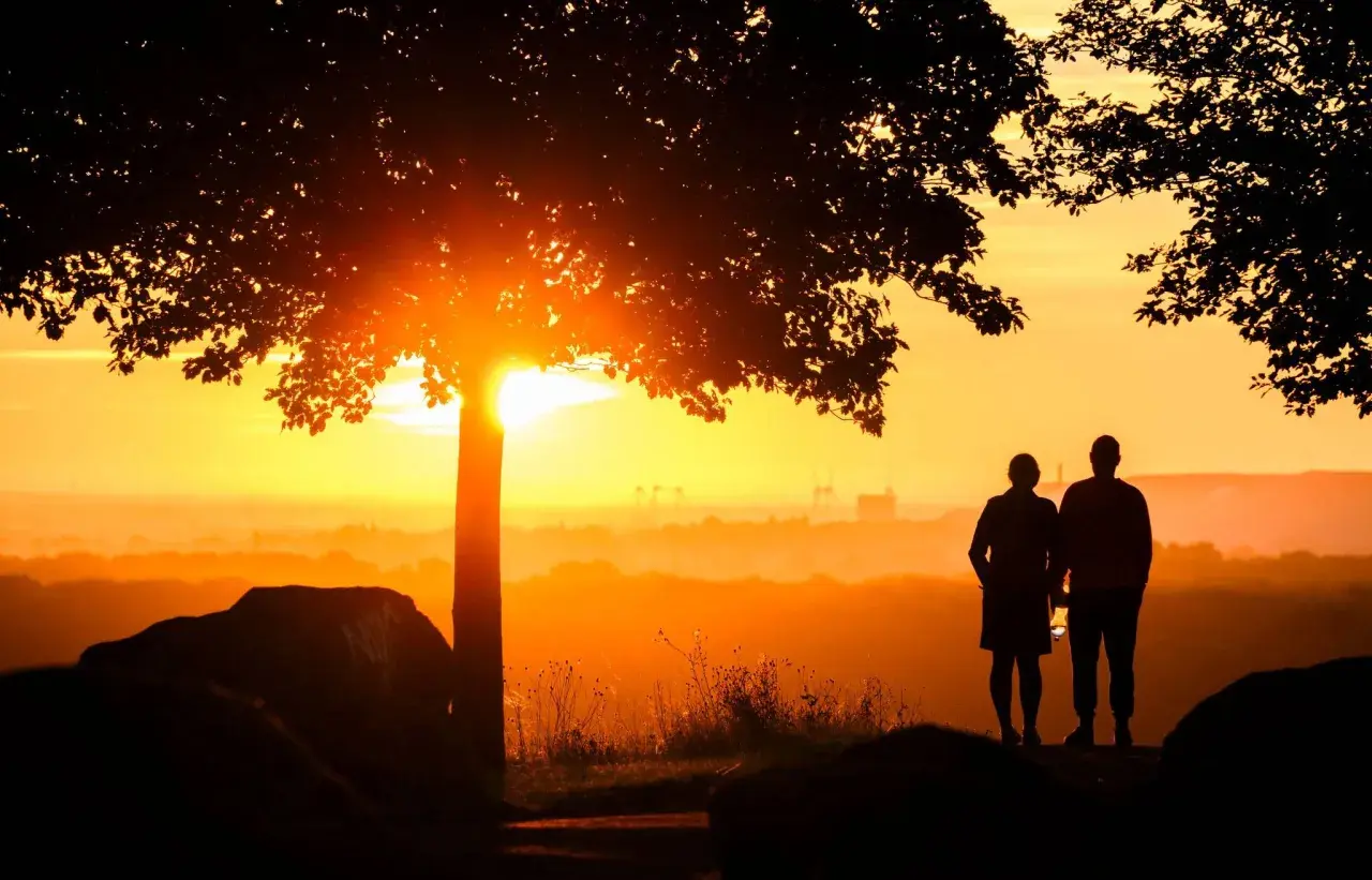 Ein Paar steht im Sonnenuntergang. Sie hat einen neuen Partner nach dem Tod ihres Ehemannes gefunden und blickt hoffnungsvoll in die Zukunft.