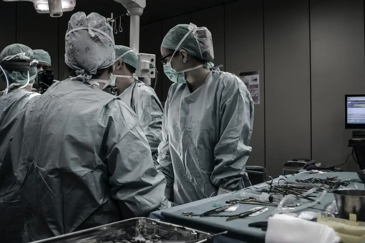 Chirurghi in sala operatoria discutono. Quanto guadagna un medico legale al mese? La risposta è complessa, ma il loro lavoro è fondamentale.