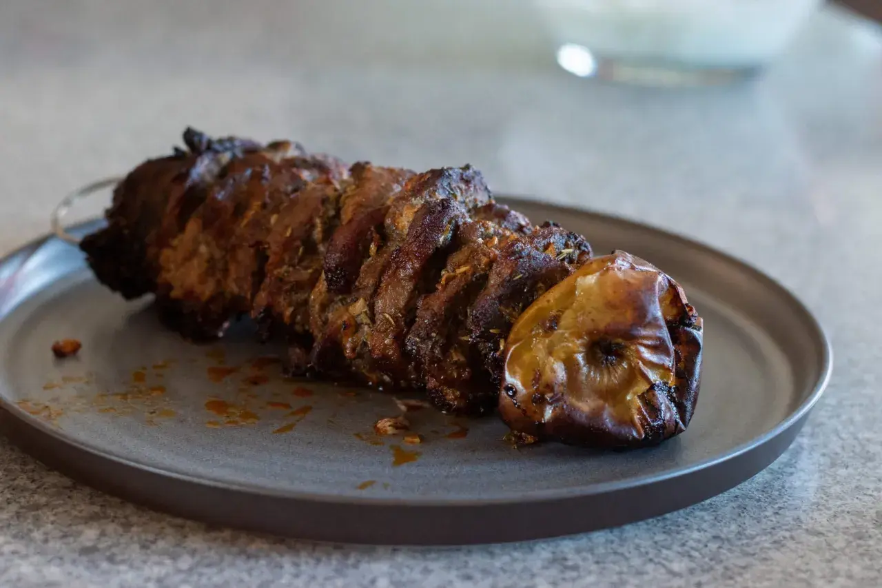 Saftigt kött på spett, perfekt för ett gyros recept. En ugnsbakad äpple ligger bredvid.