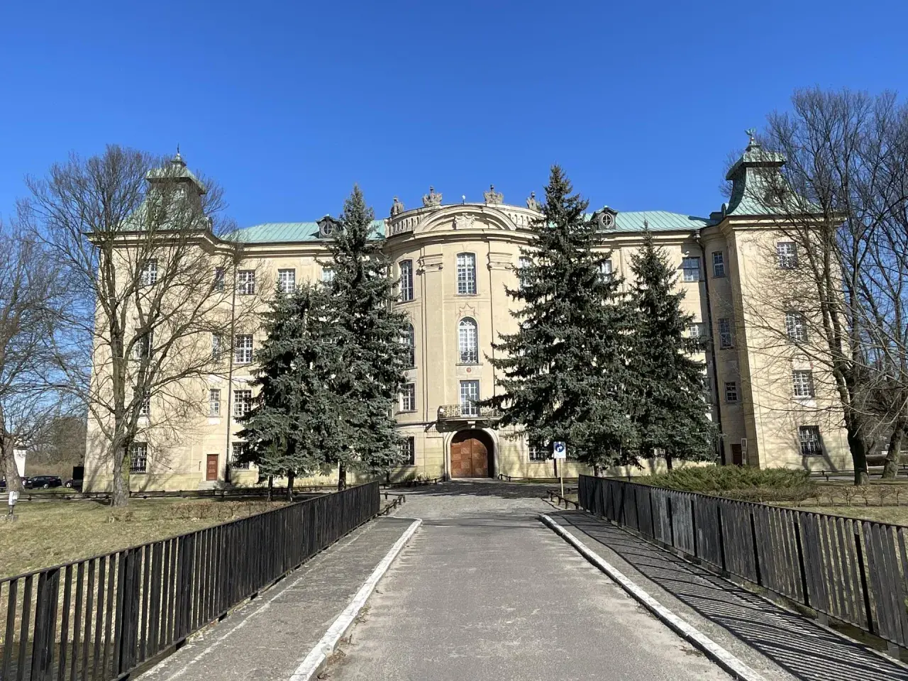 Pałac w Osiecznej, otoczony drzewami, zaprasza do odkrywania jego historii i uroków.