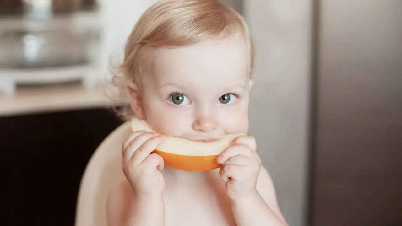 Ein süßes Baby genießt ein Stück Honigmelone.