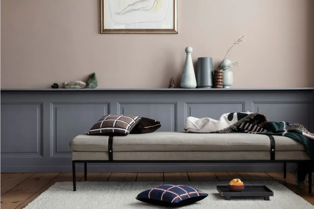 Ein Tagesbett mit Kissen und Decken vor einer Wand in einem sanften Rosaton. Welche Farbe wirkt beruhigend? Dieses Rosé schafft eine friedliche Atmosphäre.