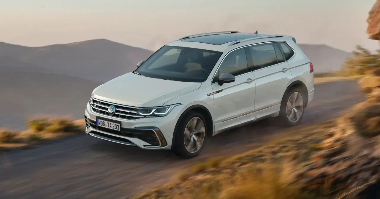 Biały Volkswagen Tiguan Allspace przemierza górską drogę.