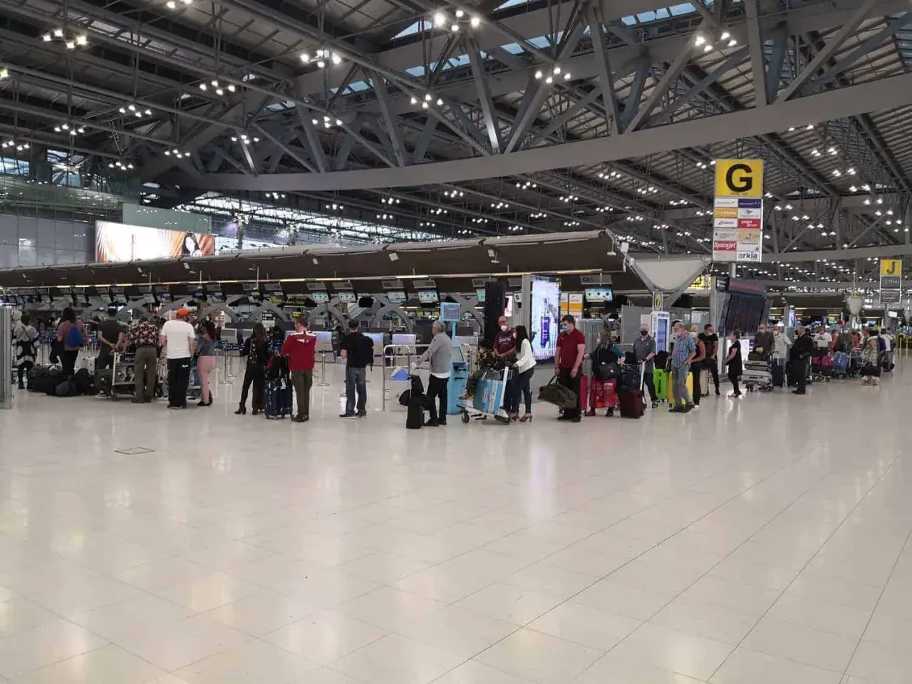 Menschen stehen in einer Schlange am Flughafen-Check-in. Gute **Kiwi com Erfahrungen** sind wichtig für entspanntes Reisen.