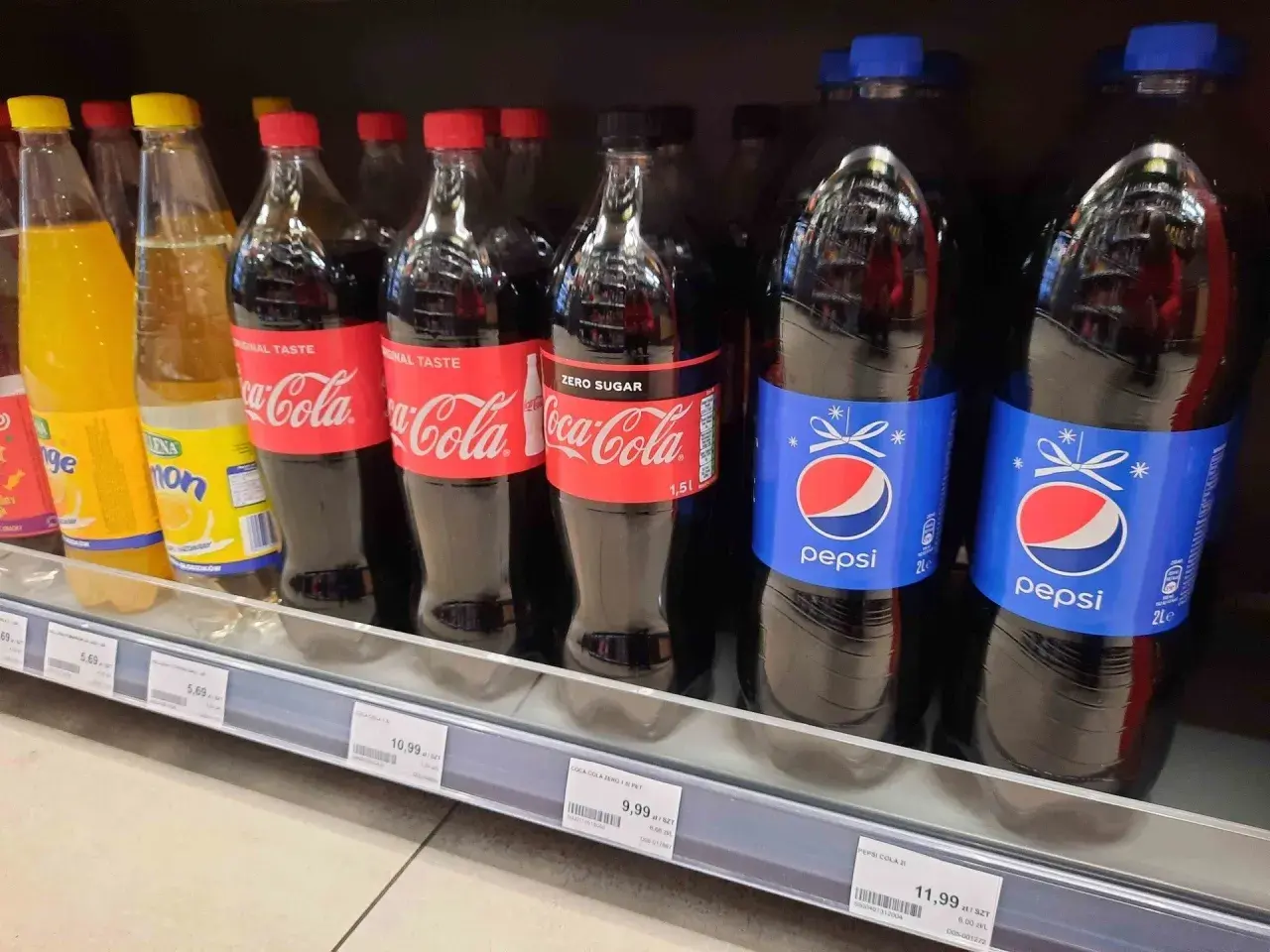 Butelki Pepsi i Coca-Coli na półce sklepowej. Cena Pepsi 2L to 11,99 zł.