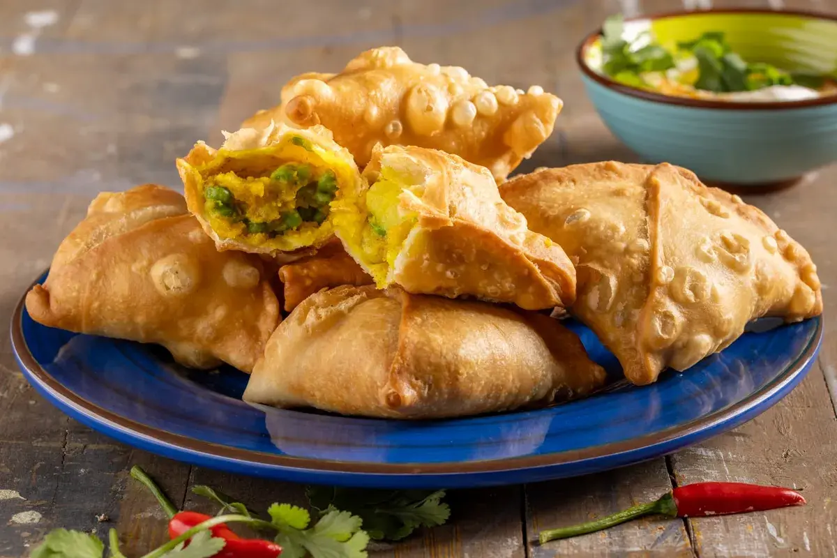 Samosa al forno dorati e croccanti, ripieni di verdure speziate. Un contorno piccante con peperoncino e coriandolo.
