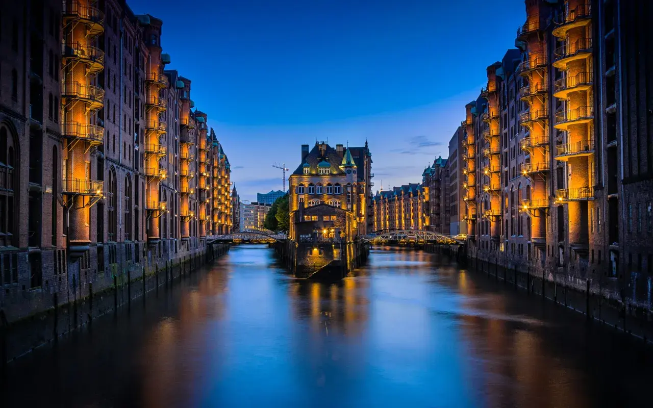 Nocny widok na Speicherstadt w Hamburgu, z kanałem i zabytkowymi budynkami magazynowymi oświetlonymi ciepłym światłem. To jedna z głównych hamburg atrakcje.