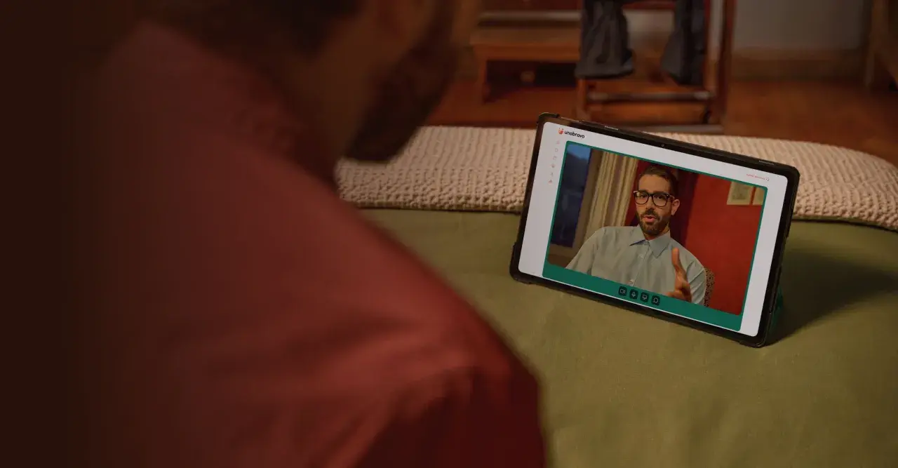 Uomo guarda un video su tablet. Sullo schermo, un uomo con occhiali parla, forse dando uno bravo recensioni.