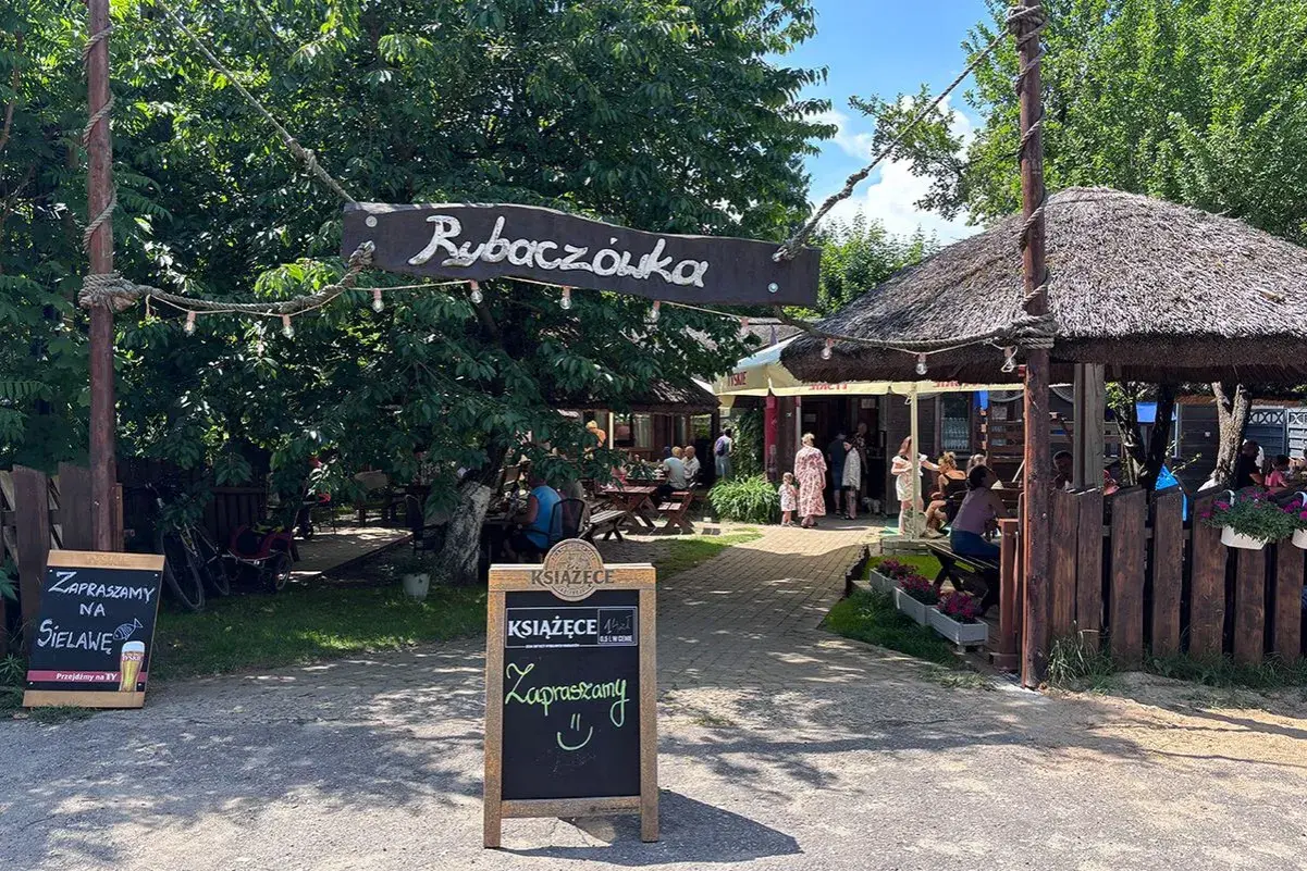 Rybaczówka zaprasza na sielawę. Letni ogródek z drewnianymi stołami i strzechą zachęca do odpoczynku.