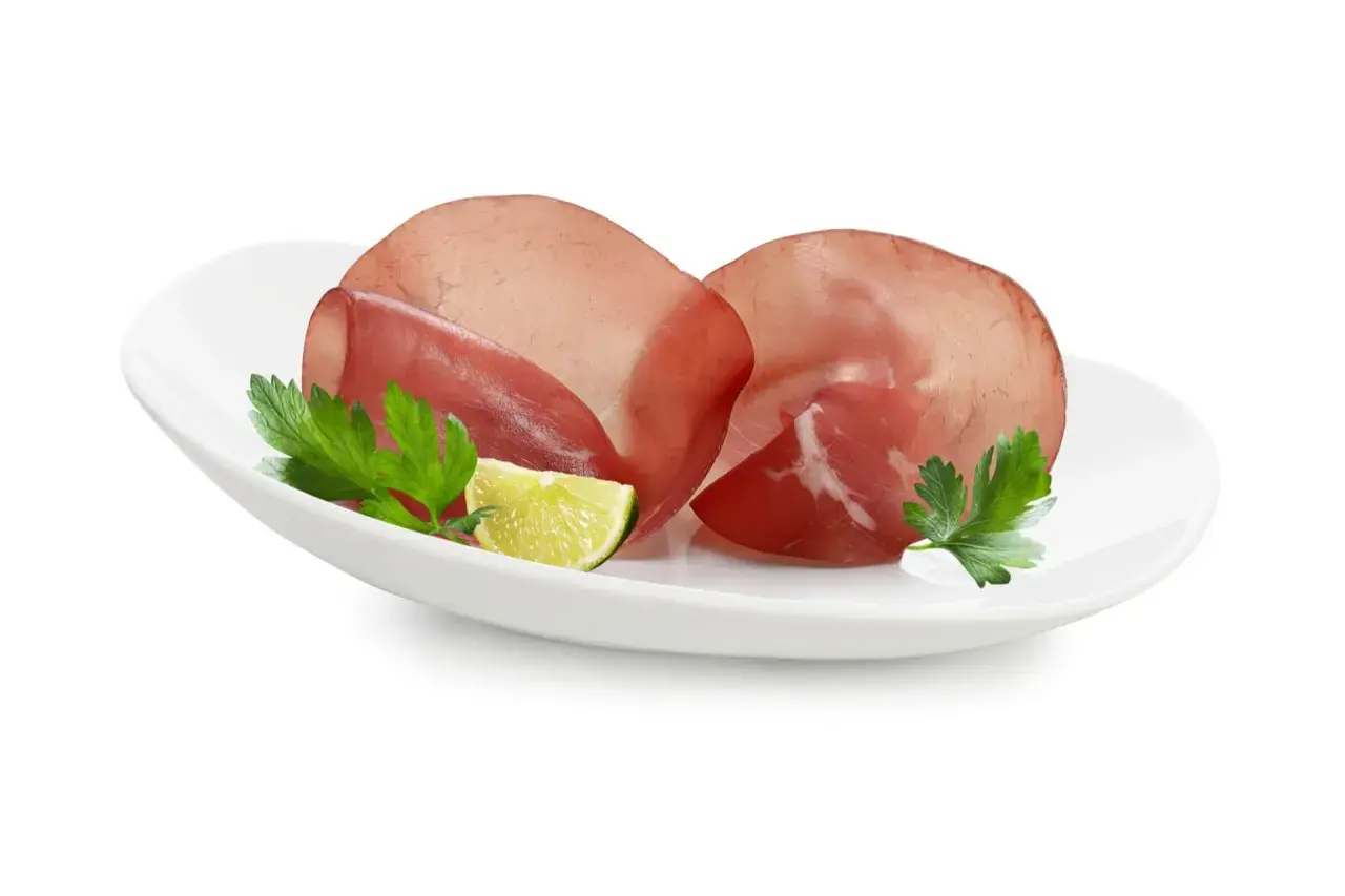 Fette di bresaola su piatto bianco con prezzemolo e lime. Ottima per un pasto leggero, scopri le calorie bresaola.