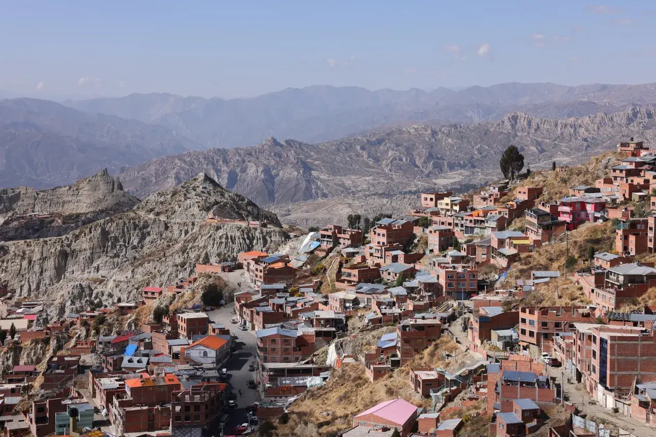 Färgglada hus klättrar uppför bergssluttningar i La Paz, bolivias huvudstad, med dramatiska berg i bakgrunden.