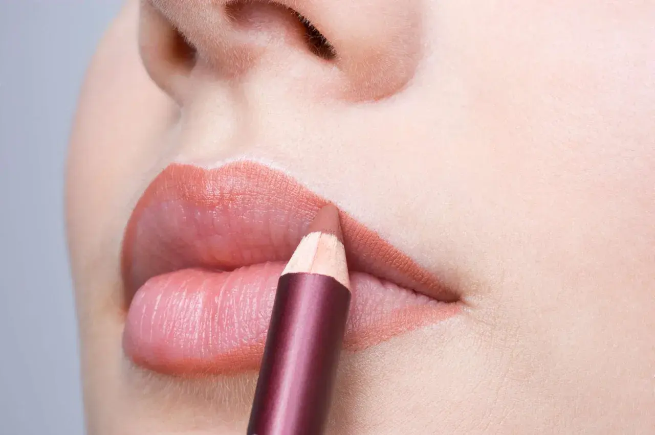 Close-up of lips with a lip liner pencil being applied.