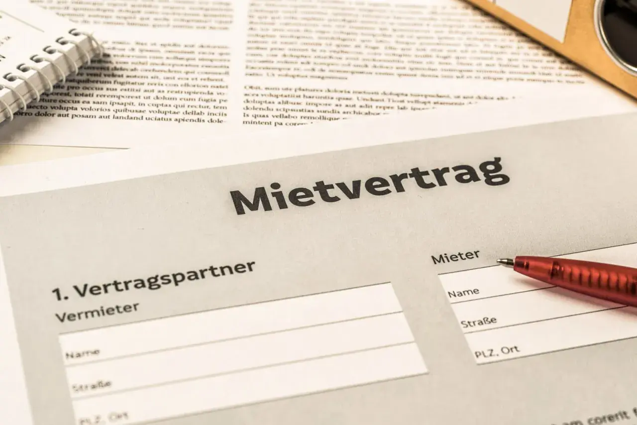 Mietvertrag mit Feldern für Vermieter und Mieter, bereit zum Ausfüllen. Ein roter Stift liegt bereit, um die Details des Mietvertrags nach § 545 BGB festzuhalten.