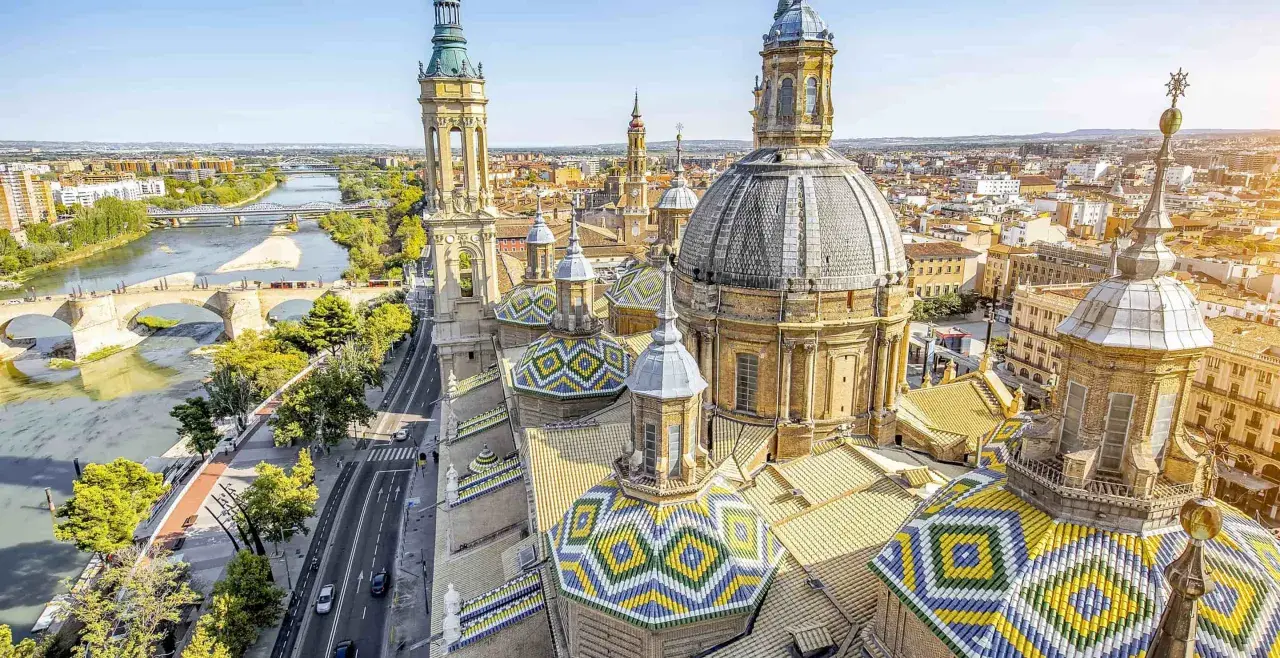 Vistas aéreas de la Basílica del Pilar en Zaragoza, con el río Ebro y puentes. Imagina un viaje en tren Sevilla Zaragoza para ver esta maravilla.