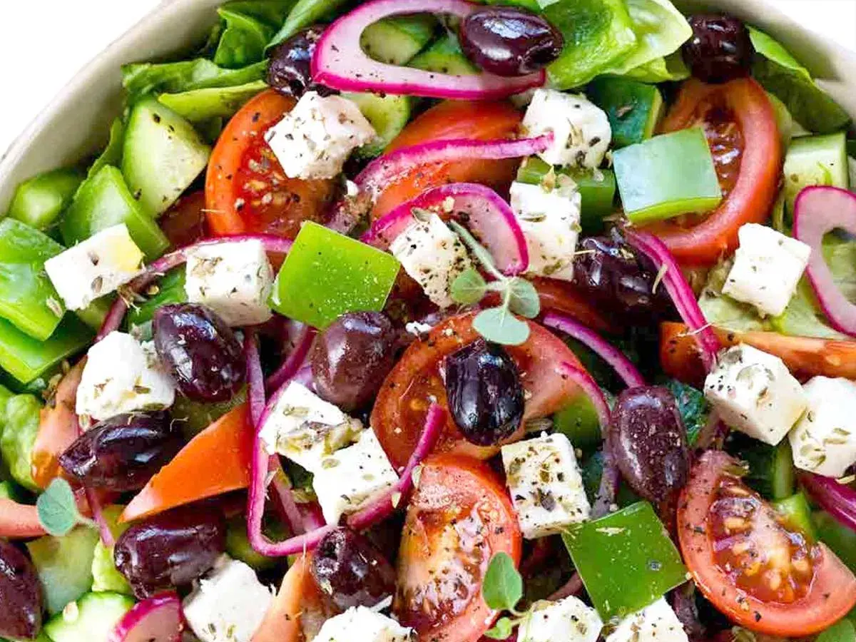 Insalata greca colorata con cubetti di feta, pomodori, olive, cetrioli e cipolla rossa. Il sapore fresco e mediterraneo è invitante.