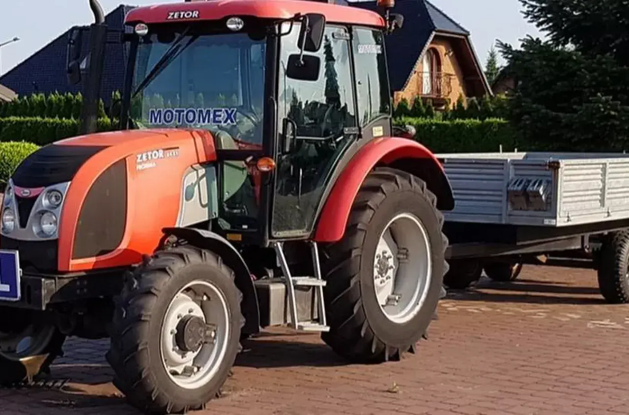 Czerwony Zetor z przyczepą, gotowy do pracy. Posiadanie prawa jazdy na traktor otwiera drogę do takich maszyn.