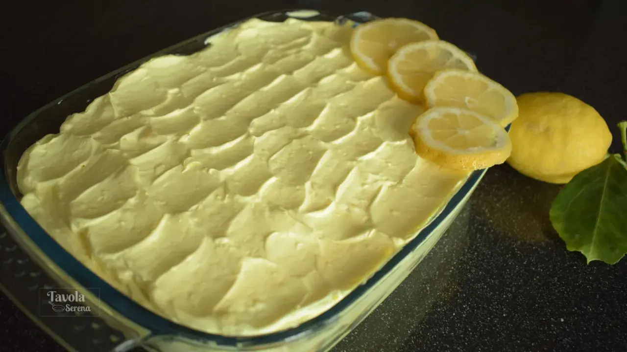 Tiramisù al limone pronto per essere gustato, decorato con fette di limone fresco e limoni interi.