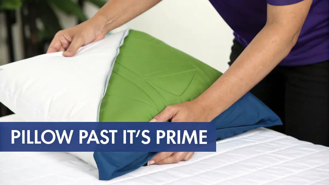 Hands adjust a pillow, hinting at how often should you change your pillows on your bed.