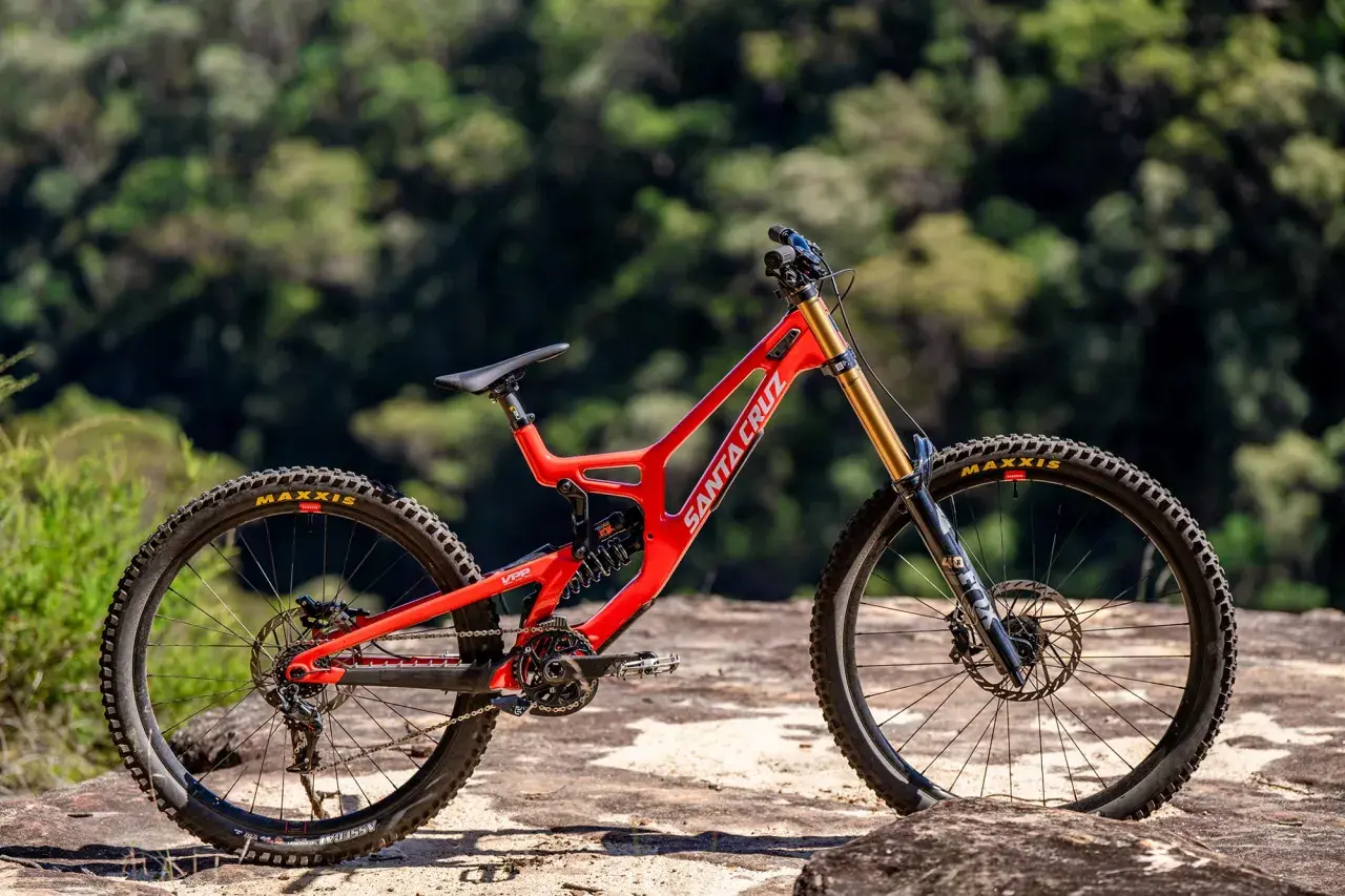 A bright red Santa Cruz V10 downhill bike sits on rocks, ready for its next review.