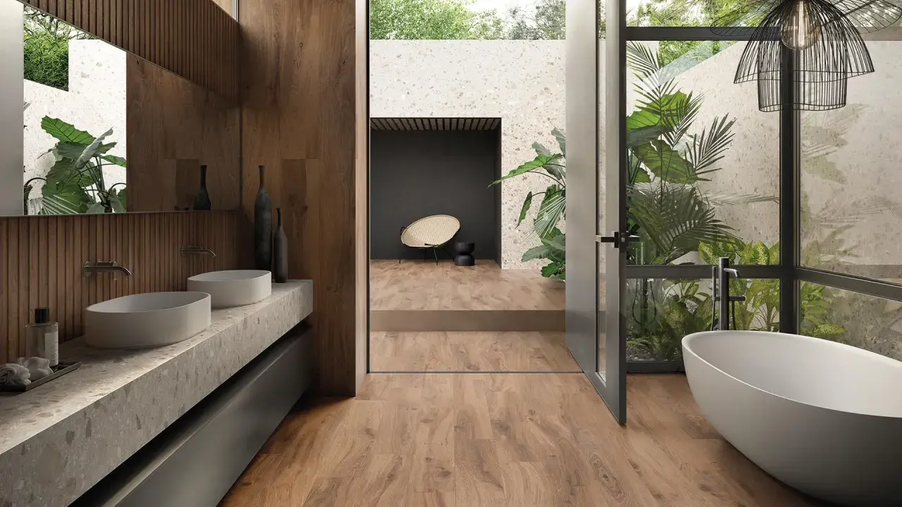 Bagno moderno con vasca freestanding, doppio lavabo e piante rigogliose. Un esempio di raffinate ristrutturazioni interne che uniscono natura e design.