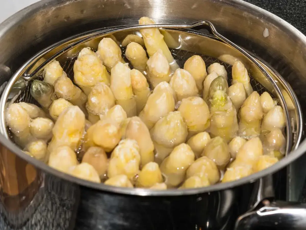 Espárragos blancos cocinándose en una olla.