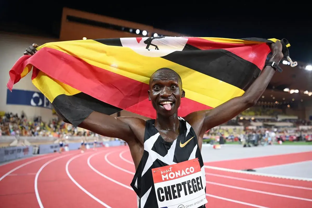 Joshua Cheptegei z flagą Ugandy świętuje swój rekord świata na 5km.