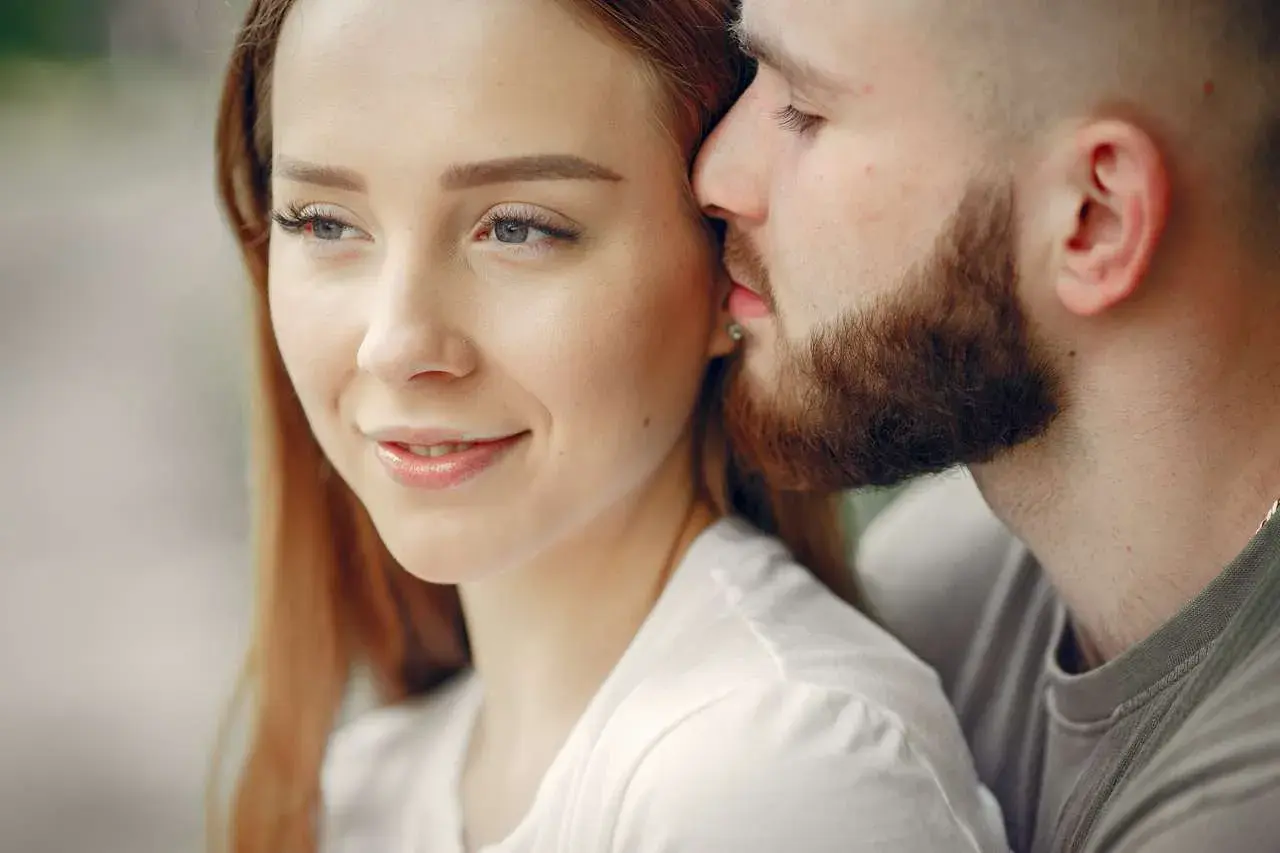 Un uomo sussurra dolcemente all'orecchio di una donna, un gesto che rivela cosa fa innamorare un uomo: la tenerezza e l'intimità.