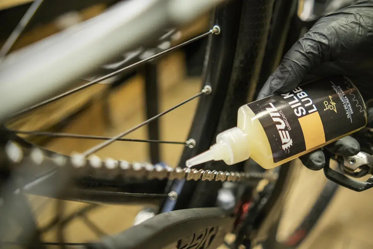 Rękawiczka z czarną rękawiczką aplikuje olej do łańcucha rowerowego. Jaki smar do łańcucha rowerowego wybrać? Ten "Silk Lube" wygląda obiecująco.